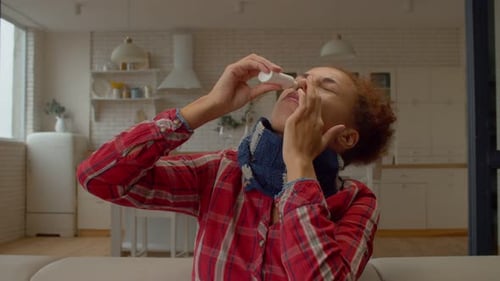 Portrait of Ill African Female with Runny Nose Using Nasal Spray for Treatment