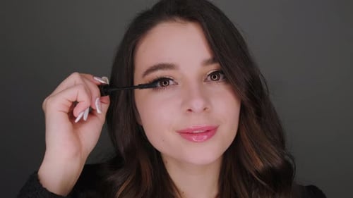 Woman Applies Mascara in Close-Up Studio Shot