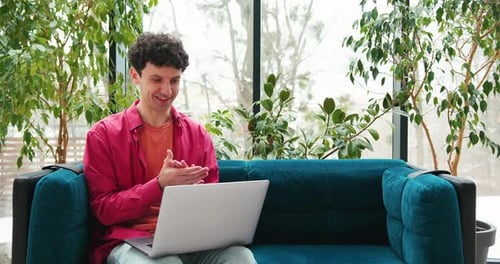 Smiling Man Businessman Using Laptop Working in Modern Office Having Video Call Sitting on Sofa