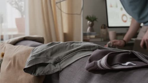 Anonymous Man Grabbing Clothing Items off Couch after Wiping Work Desk