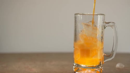 Pouring Refreshing Orange Soda Into Glass Mug With Ice