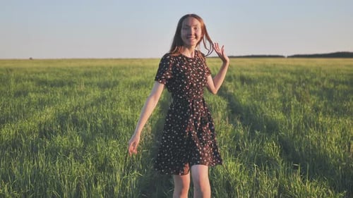 A Happy Girl Walks in the Field in the Evening