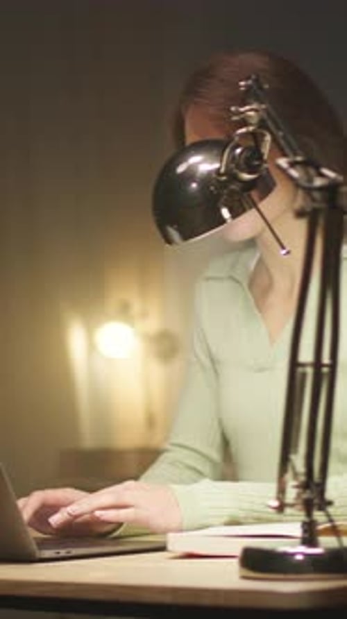 Woman Works on Laptop at Desk at Night