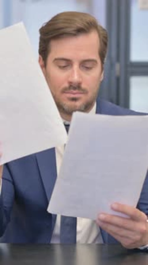 Excited Man Reading Documents Celebrating Success in Office
