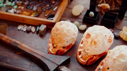 Des pierres précieuses, des cristaux et des coquillages décoratifs sculptés sont posés sur la table en bois