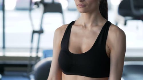 Attractive young woman works out using dumbbells for fitness and health in gym