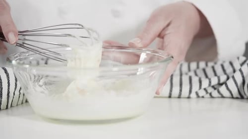 Person Mixing Thick White Batter in Glass Bowl