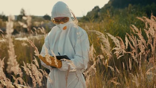 Person in Protective Suit Taking Notes in Field