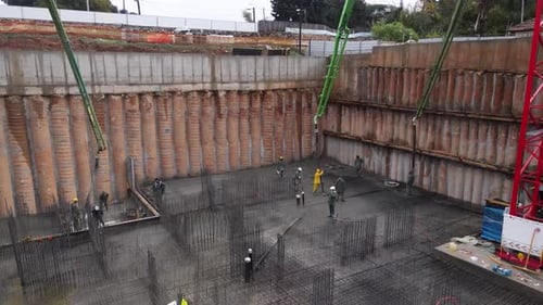 Aerial view of construction workers laying cement using automatic pump, Israel