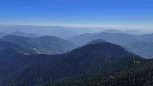 Serene Mountain Range With Lush Green Forest Under Blue Sky