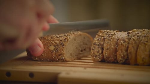 Hand Slicing Seeded Bread Loaf on Cutting Board