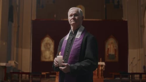 Portrait of Elderly Priest Holding Candle in Church