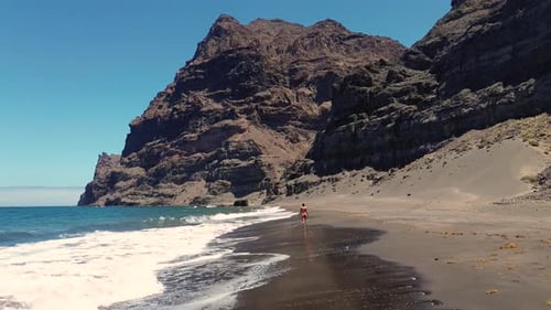 Idyllic scene of a woman relaxing unwinding at unspoiled virgin beach in summer at Spain