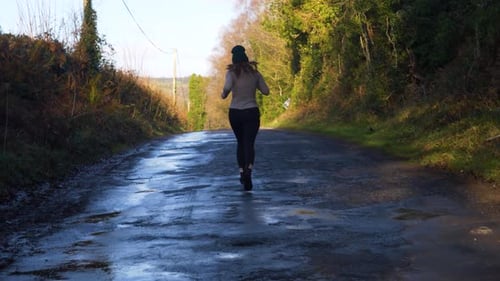 Woman Jogging on a Quiet Country Road in Sunny Weather for Peaceful Exercise