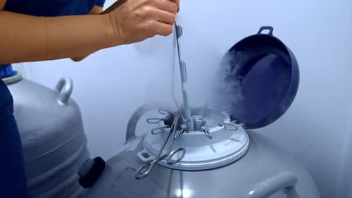 Laborärztin, die die Proben mit flüssigem Stickstoff aus dem Reservoir extrahiert.