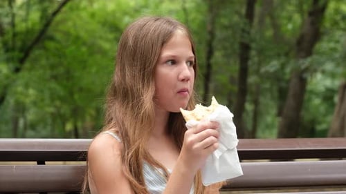 Close Up Girl Eating Street Food on Bench in Park Green Nature Background