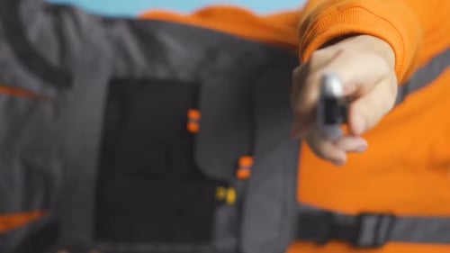 Vertical Video of Repairman with Orange Shirt and Overalls Handing Utility Knife