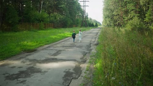 Children Walking Alone Along Tarred Road Beside Tall Grass