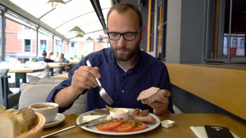 Handsome Young Man Eating Breakfast in Restaurant 30s