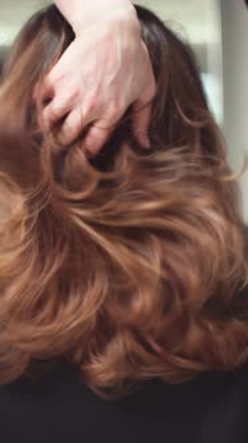 Close up of hand running through brown hair