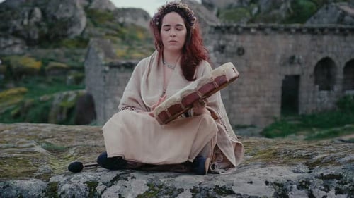 spiritual woman playing a shamanic drum in a beautiful medieval village long shot