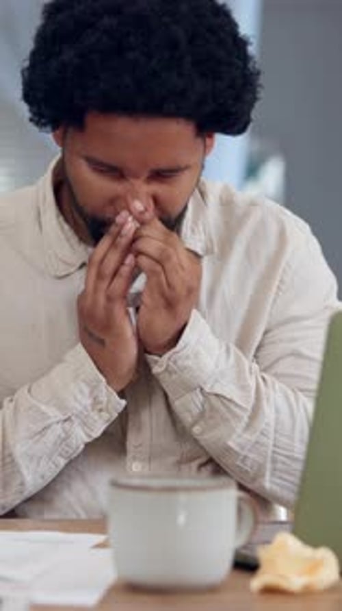 Allergy, sneeze and black man in home office with laptop, tissue and burnout from flu