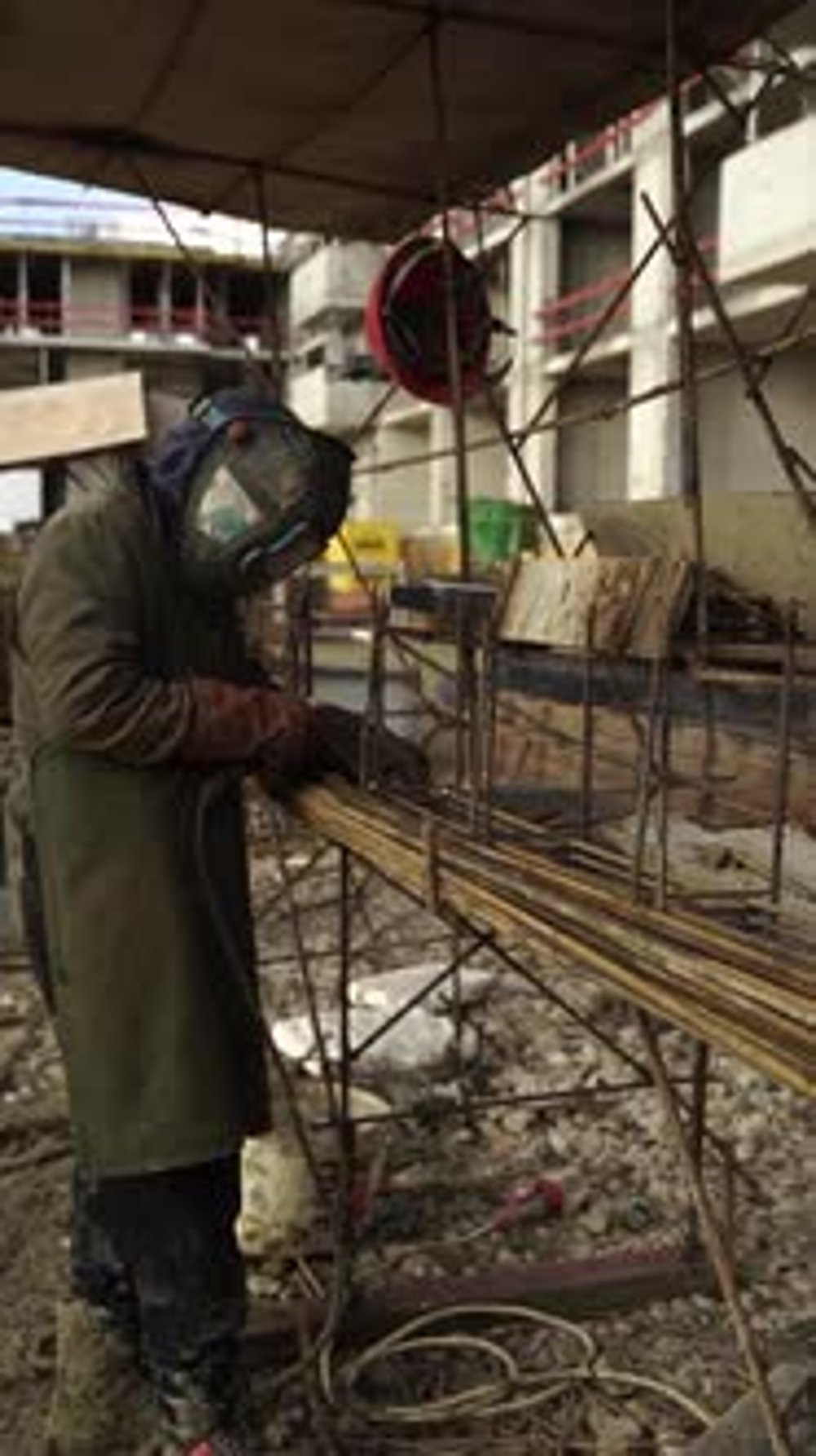 Welder creating sparks on rebar frame at construction site, vertical ...