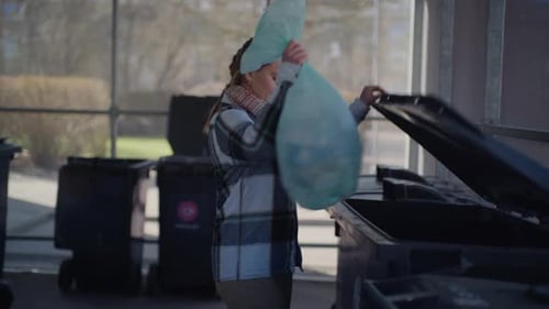 Woman Disposing Trash Bag In Trash Bin