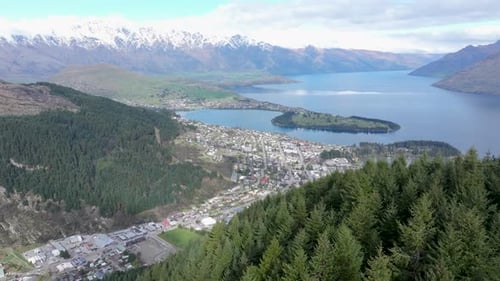 Aerial view of Queenstown, revealing over trees to lake and mountain scenery, New Zealand.