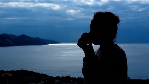 Silhouette of a Woman Drinking Coffee Near Ocean