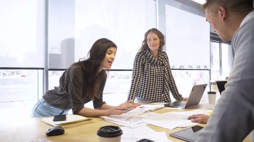 Three Business People Discussing Data in Bright Office