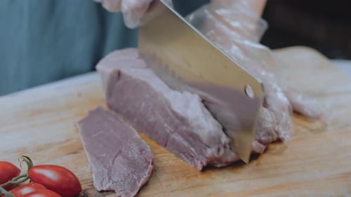Chef Slices Meat on Cutting Board in Kitchen