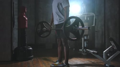 Man Lifting Weights in Dark Gym