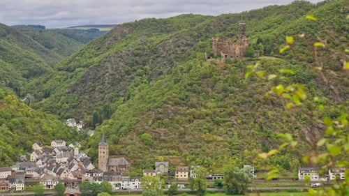 Rural village near the Rhine River with steep towering hills including a medieval castle on the hill