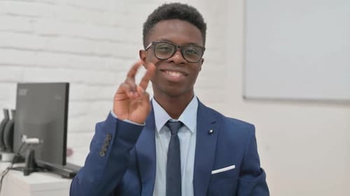 Smiling Man Giving Peace Sign in Office