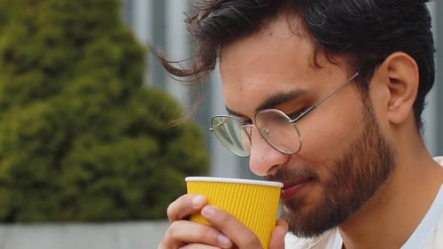 Happy Indian Man Enjoying Drinking Morning Coffee Hot Drink Relaxing Taking a Break in City Street