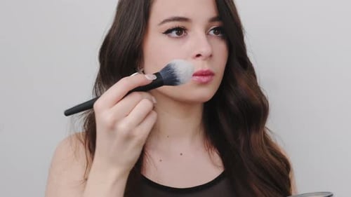 Young Woman Applying Makeup with Brush and Powder