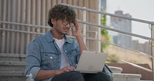 Young Adult Uses Laptop on Urban Steps