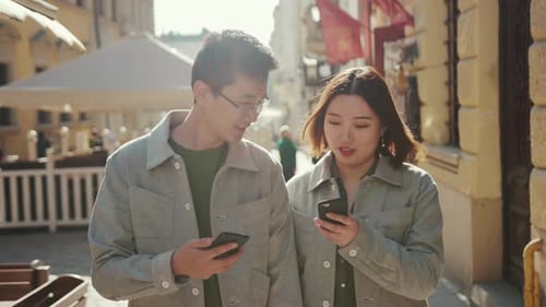 NEW YORK, 5 avril 2017 Un jeune couple asiatique marche, utilise le téléphone, parle, sourit, femme d'affaires, heureuse, centre-ville