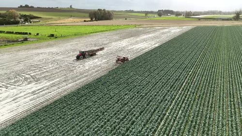 Aerial view of tractor with mounted seeder performing direct seeding of crops on plowed agricultural
