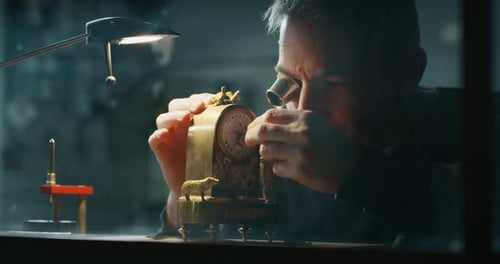 Slow motion close up of a professional watchmaker repairer working on a vintage mechanism clock in