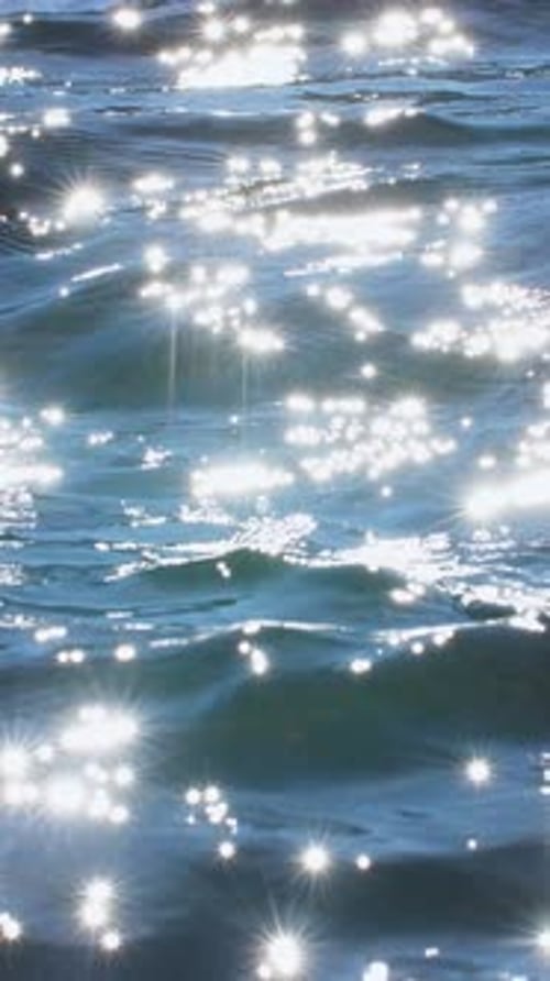 Sparkling Sunlight Reflects on Calm Water Surface in Serene Natural Setting