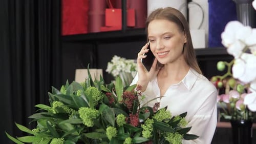 Smiling Woman Talking on Phone With Flowers Nearby