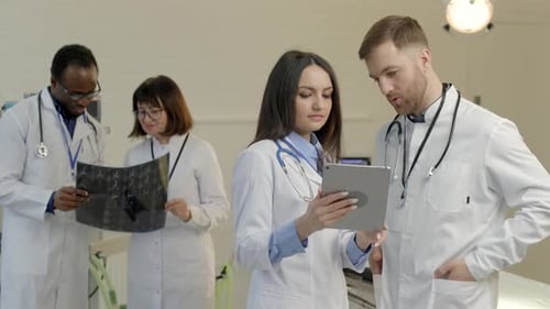 Medical Team Examining X-Ray and Tablet in Hospital