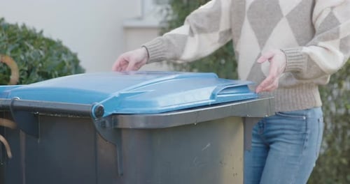 Woman Opens Recycling Container Outdoors