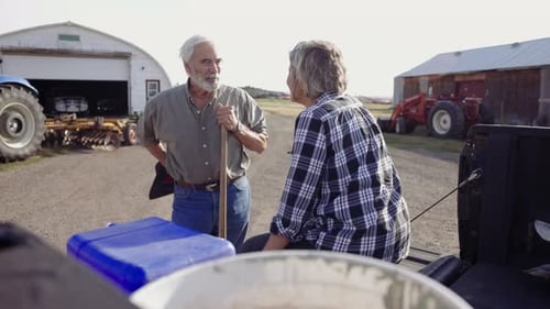 Senior Farmer Couple Talking at Pickup Truck on Sunny Farm 10 Seconds or Greater