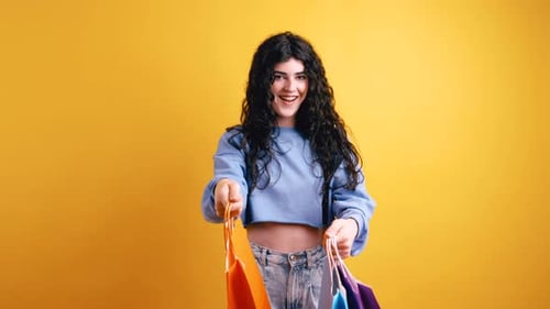 Cheerful Woman Holding Colorful Shopping Bags Against Yellow Backdrop