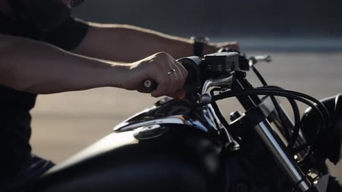 Motorcycle Handlebars with a Helmeted Operator in Daylight