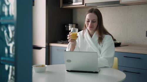Woman with Laptop and Juice in Modern Kitchen
