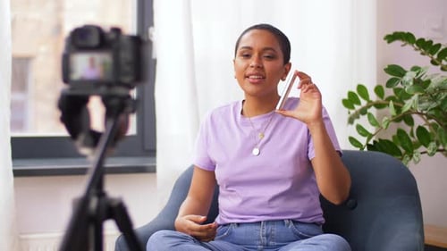 Feliz vloguera de belleza afroamericana reseña el maquillaje en casa para su blog de vídeos